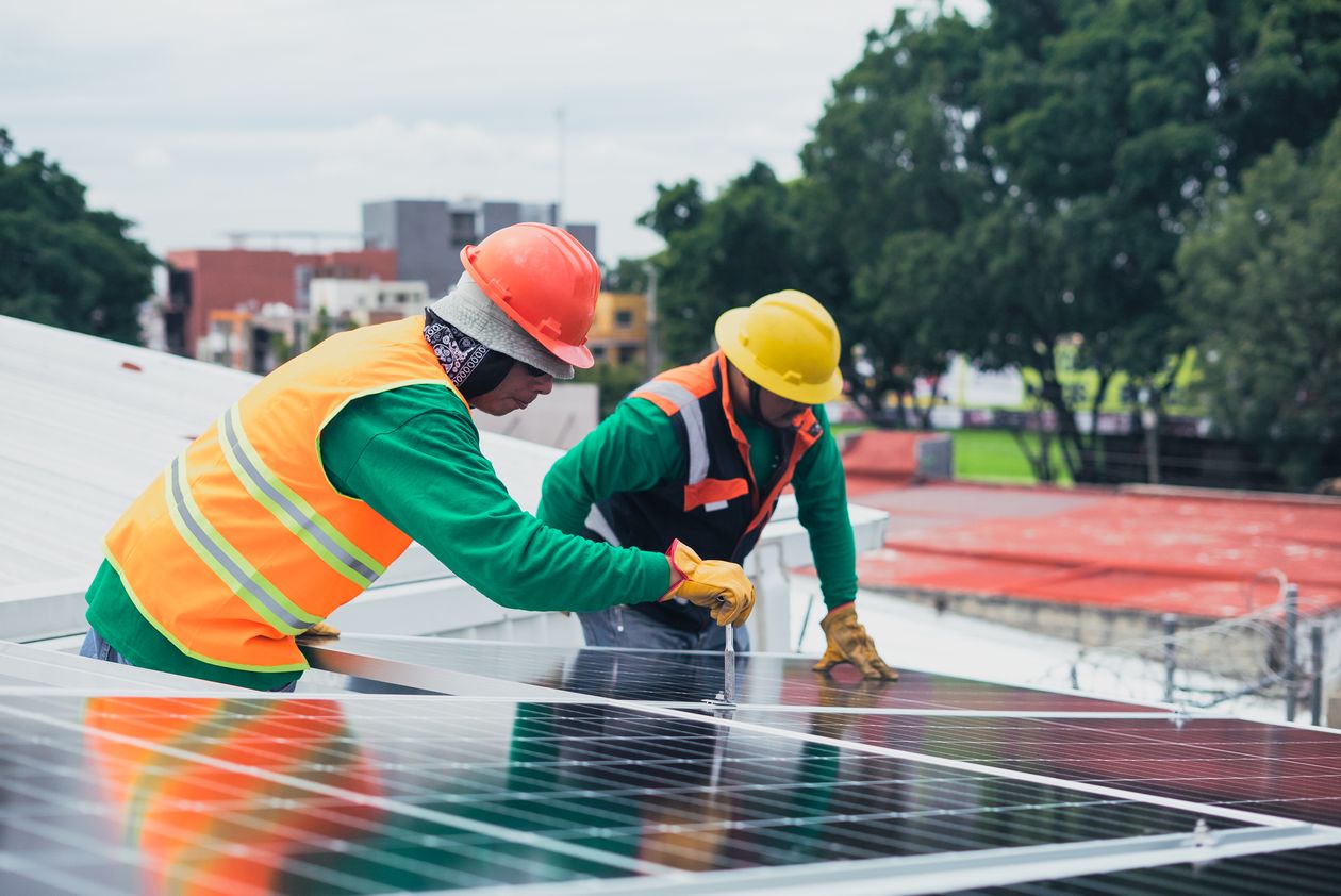 Two workers installing rooftop solar panels