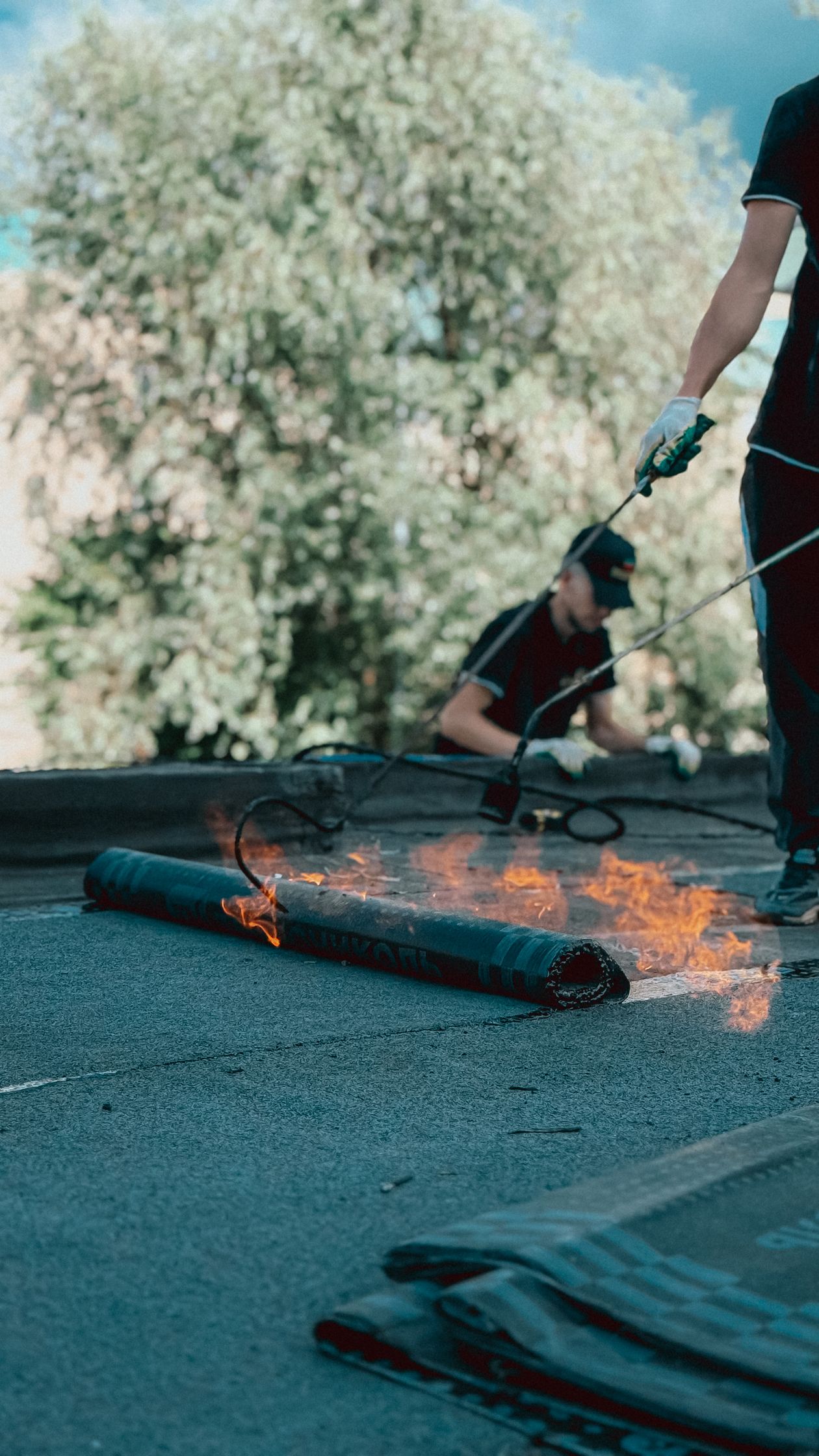 Roofers torch-applying modified bitumen membrane