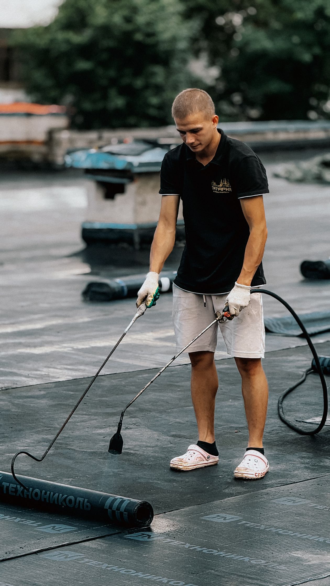 Roofer heat-welding a thermoplastic membrane seam on a flat roof